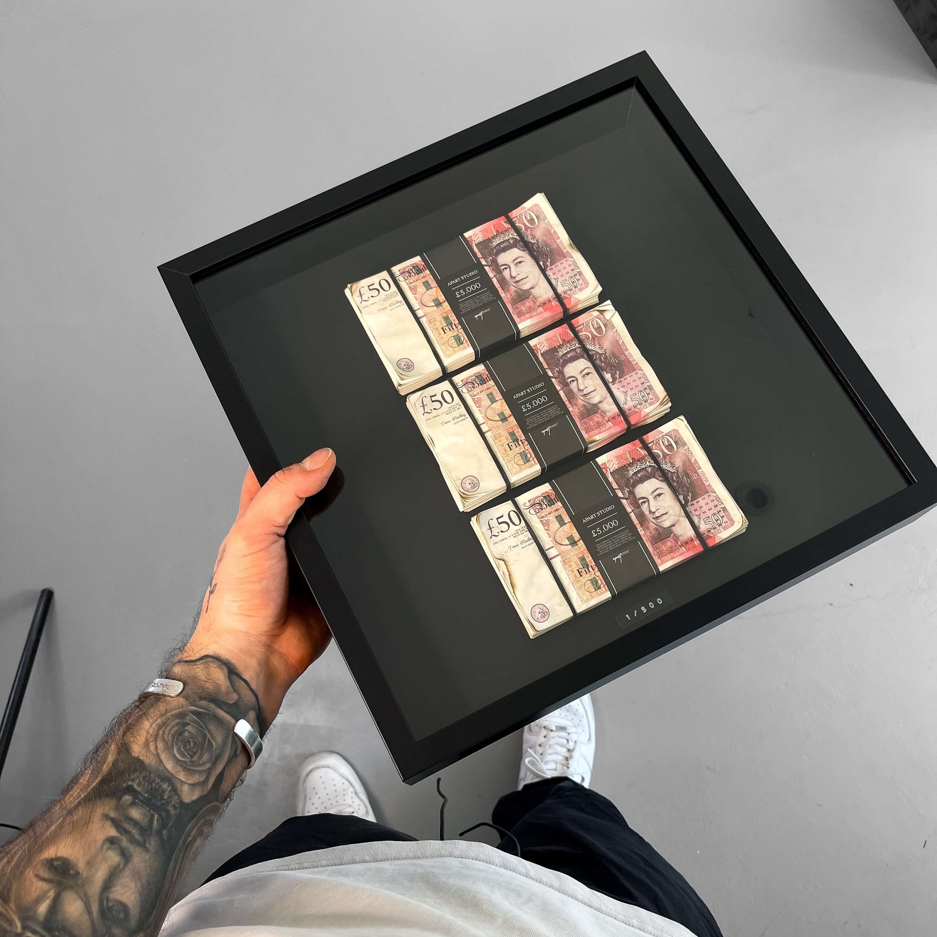 Aged Triple Stacked Frame GBP held in hand, three stacks of aged British fifty pound notes behind glass in a deep black frame by Apart Studio